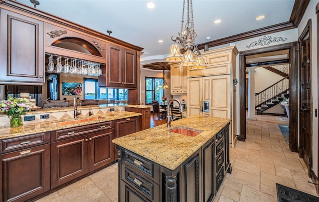 kitchen with pendant lighting, light stone counters, ornamental molding, and sink