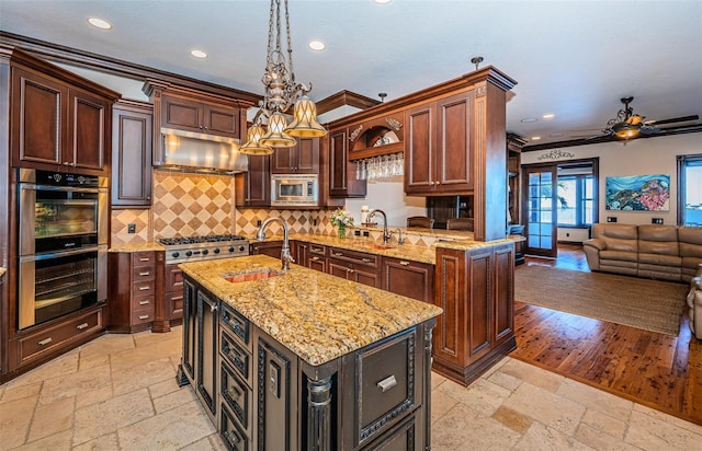 kitchen featuring sink, a center island with sink, stainless steel appliances, and ornamental molding