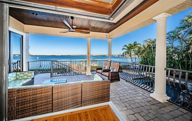 view of patio / terrace with ceiling fan, a water view, and an outdoor living space