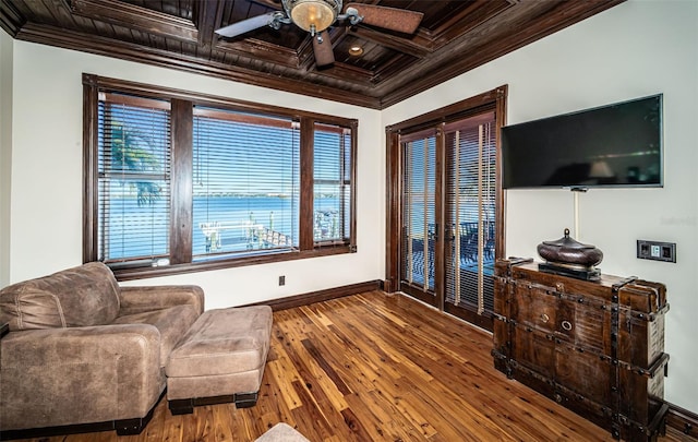 living area featuring wood-type flooring, ceiling fan, crown molding, and coffered ceiling