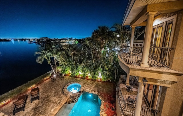 exterior space featuring a patio area, an in ground hot tub, and a water view