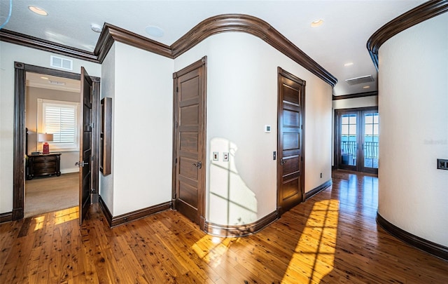 hall with crown molding, french doors, and wood-type flooring