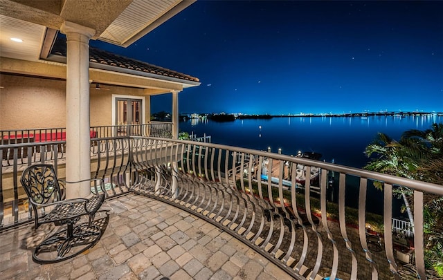 balcony at night featuring a water view