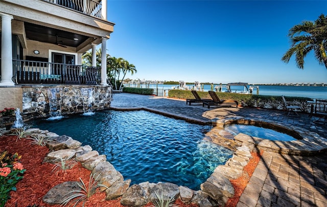 view of pool with ceiling fan, pool water feature, an in ground hot tub, a water view, and a patio