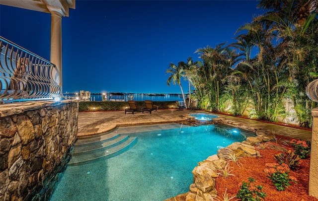 pool at twilight featuring an in ground hot tub and a patio