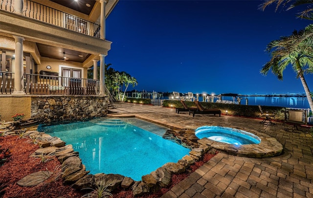 pool at twilight featuring an in ground hot tub, french doors, ceiling fan, and a patio