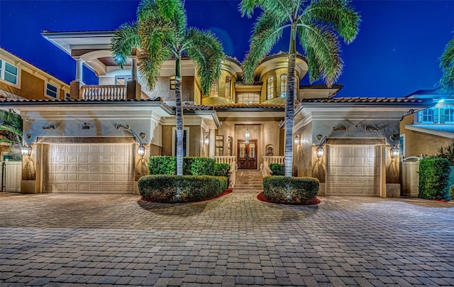 view of front of property featuring a tiled roof, a balcony, decorative driveway, and stucco siding