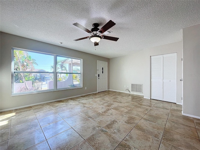 tiled empty room featuring ceiling fan and a textured ceiling