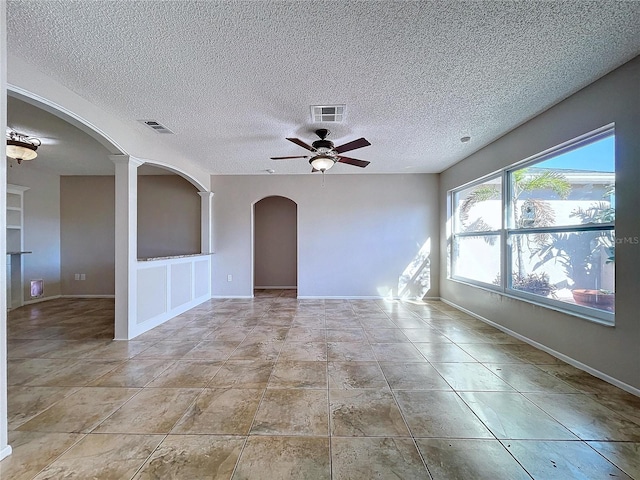 tiled empty room with built in shelves, a textured ceiling, and ceiling fan