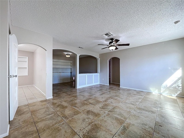 spare room with ceiling fan, built in features, and a textured ceiling