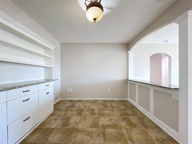 unfurnished dining area with built in features and a textured ceiling