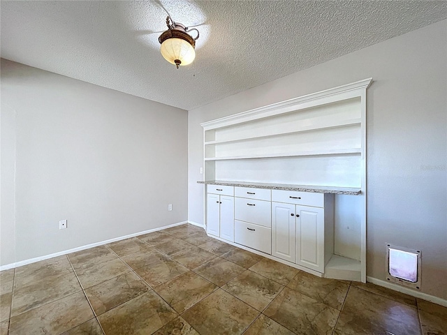 interior space with built in shelves, a textured ceiling, and heating unit