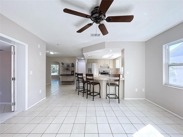 kitchen featuring a kitchen breakfast bar, plenty of natural light, stainless steel appliances, and a textured ceiling