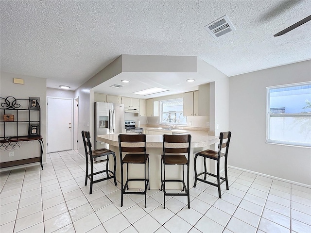 dining area with ceiling fan, light tile patterned flooring, sink, and a textured ceiling