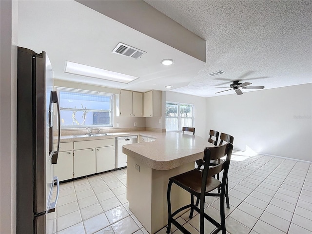 kitchen featuring dishwasher, kitchen peninsula, ceiling fan, a kitchen bar, and stainless steel fridge with ice dispenser