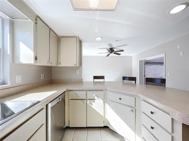 kitchen featuring dishwasher, ceiling fan, light tile patterned floors, a textured ceiling, and kitchen peninsula