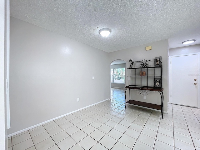 tiled empty room with a textured ceiling