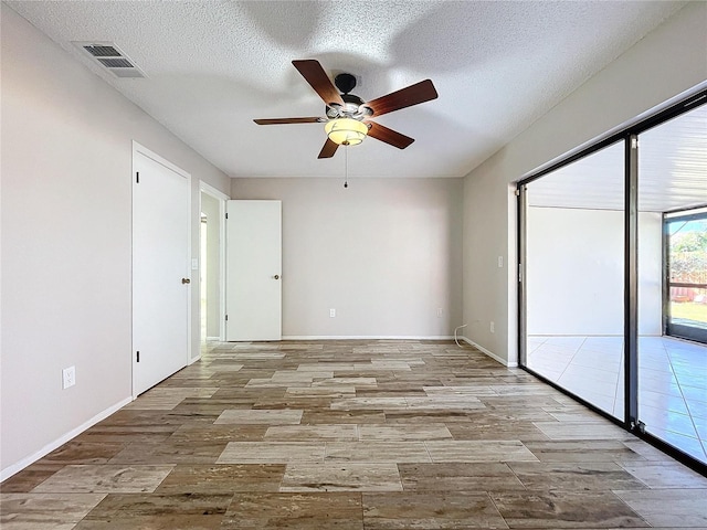 empty room with a textured ceiling, light hardwood / wood-style flooring, and ceiling fan