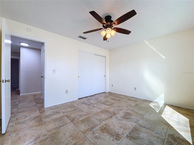 unfurnished bedroom featuring ceiling fan, a textured ceiling, and a closet