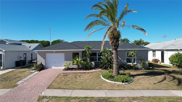 ranch-style home featuring a front yard, a garage, and central AC unit