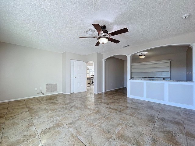 unfurnished living room with built in shelves, ceiling fan, and a textured ceiling