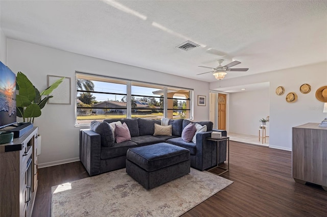 living room featuring dark hardwood / wood-style floors, ceiling fan, and a textured ceiling