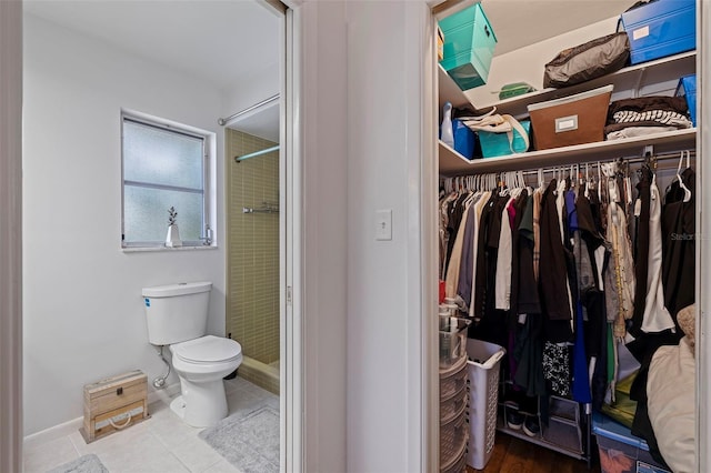 interior space featuring tiled shower, tile patterned flooring, and toilet