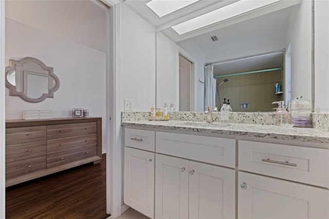 bathroom featuring wood-type flooring, vanity, a skylight, and a shower with curtain