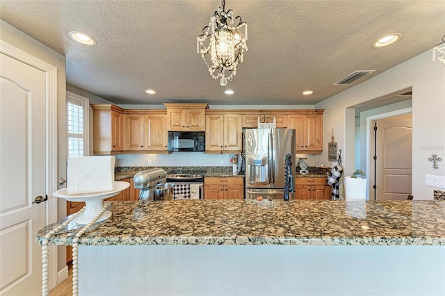 kitchen featuring a notable chandelier, dark stone countertops, pendant lighting, a textured ceiling, and appliances with stainless steel finishes