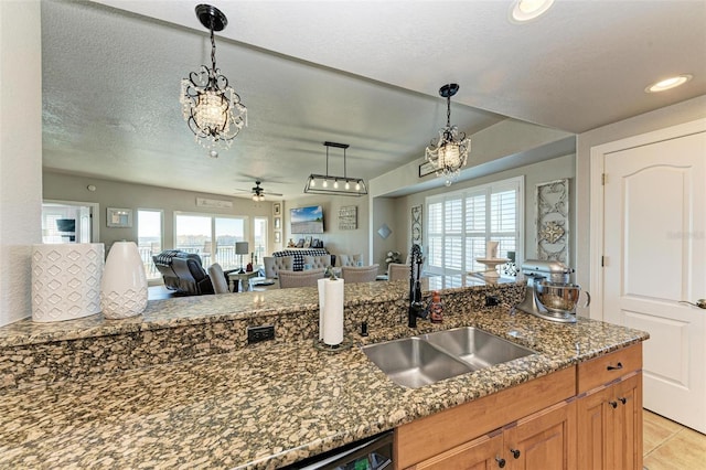 kitchen featuring pendant lighting, ceiling fan, a healthy amount of sunlight, and dark stone countertops