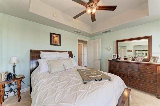 bedroom featuring ceiling fan, a raised ceiling, and light colored carpet