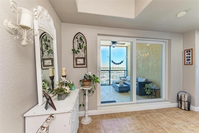 doorway featuring ceiling fan and light tile patterned floors