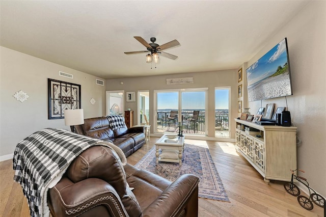 living area featuring light wood-type flooring, baseboards, a ceiling fan, and visible vents