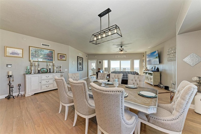 dining space with baseboards, light wood-style flooring, a textured ceiling, a ceiling fan, and visible vents
