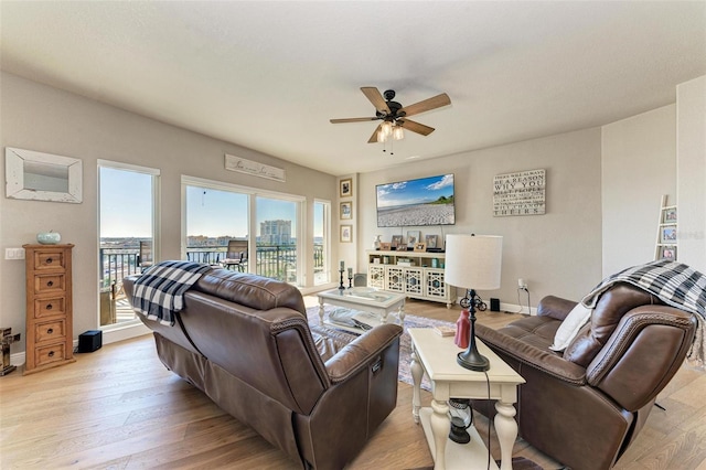 living room with baseboards, a ceiling fan, and light wood-style floors