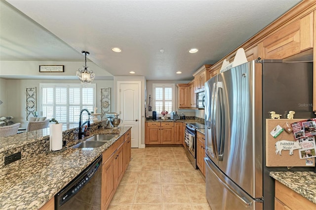 kitchen with dark stone countertops, light tile patterned floors, appliances with stainless steel finishes, pendant lighting, and a sink