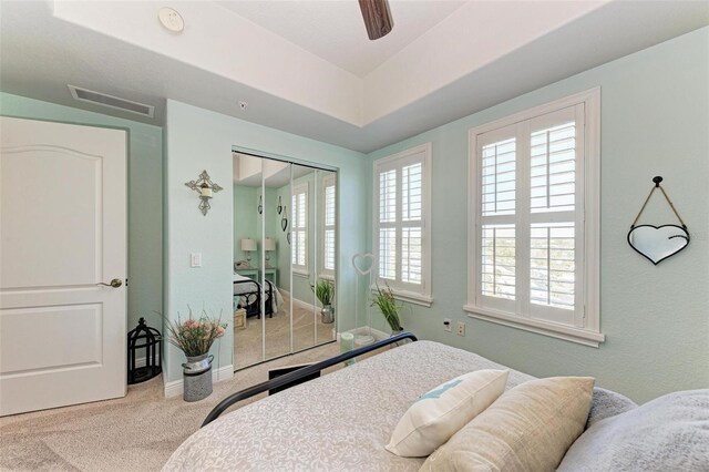 carpeted bedroom with a closet, baseboards, a ceiling fan, and visible vents