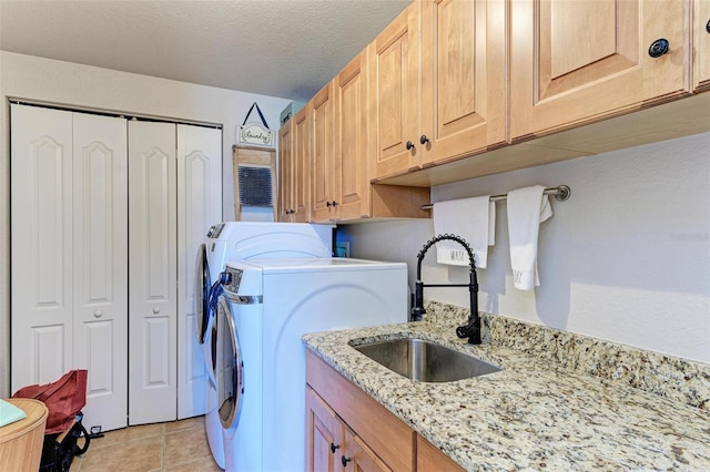 clothes washing area with independent washer and dryer, a textured ceiling, light tile patterned flooring, a sink, and cabinet space