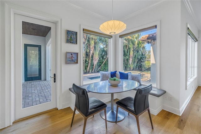 dining area with breakfast area, light hardwood / wood-style floors, and ornamental molding