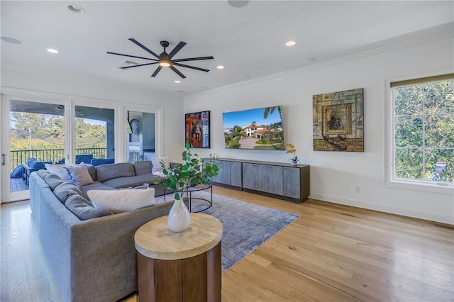 living room with crown molding, plenty of natural light, ceiling fan, and light wood-type flooring