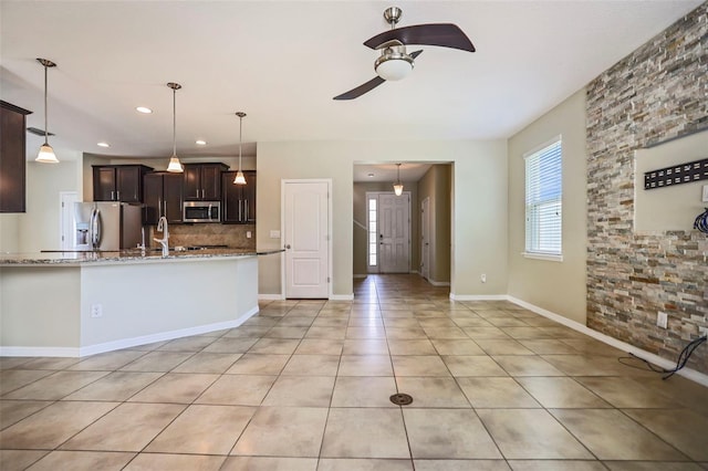 kitchen featuring dark brown cabinets, ceiling fan, light stone counters, and appliances with stainless steel finishes