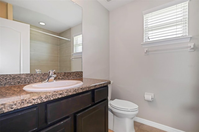 bathroom with tile patterned floors, plenty of natural light, toilet, and vanity