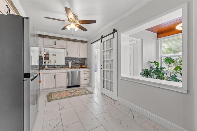 kitchen featuring tasteful backsplash, stainless steel appliances, sink, a barn door, and white cabinets