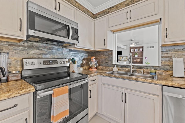 kitchen with tasteful backsplash, sink, white cabinets, and appliances with stainless steel finishes