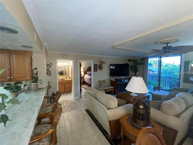 living room with ceiling fan, ornamental molding, and light wood-type flooring