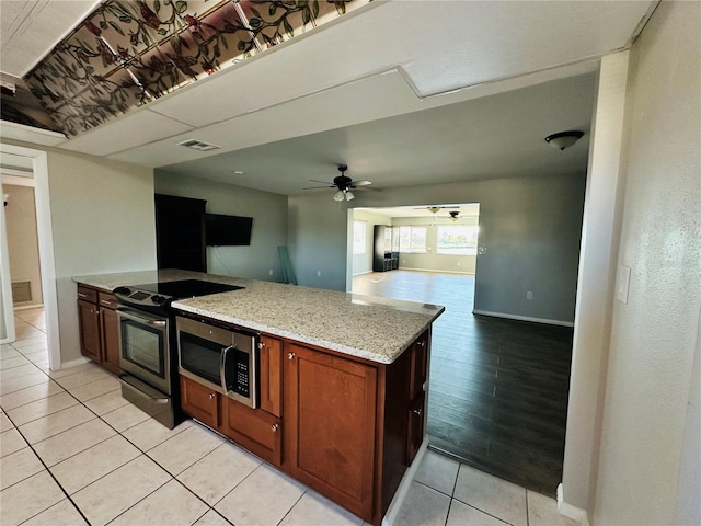 kitchen with light tile patterned floors, electric range, light stone countertops, and ceiling fan