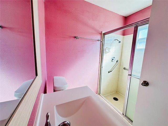 bathroom featuring a shower with door and toilet