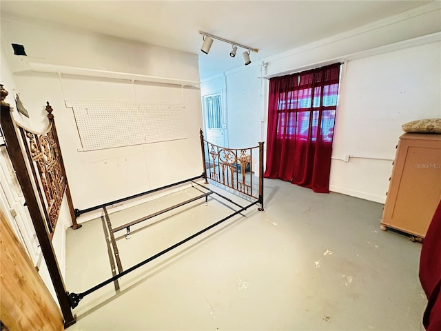 bedroom featuring rail lighting and concrete floors