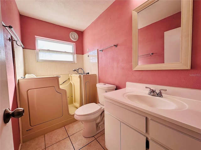 bathroom featuring a tub to relax in, tile patterned floors, toilet, washer / dryer, and vanity