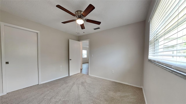 unfurnished bedroom featuring a textured ceiling, light colored carpet, and ceiling fan